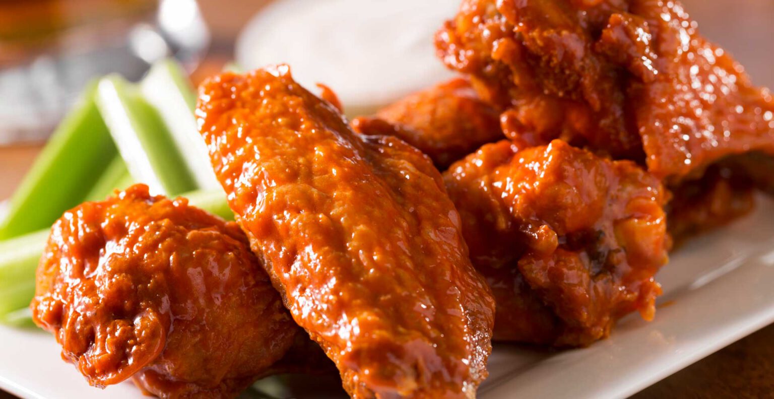 A close up of buffalo wings and celery sticks.