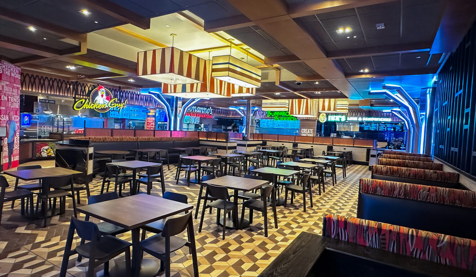 The layout of restaurant with vibrant lights and many chairs and tables to sit at.